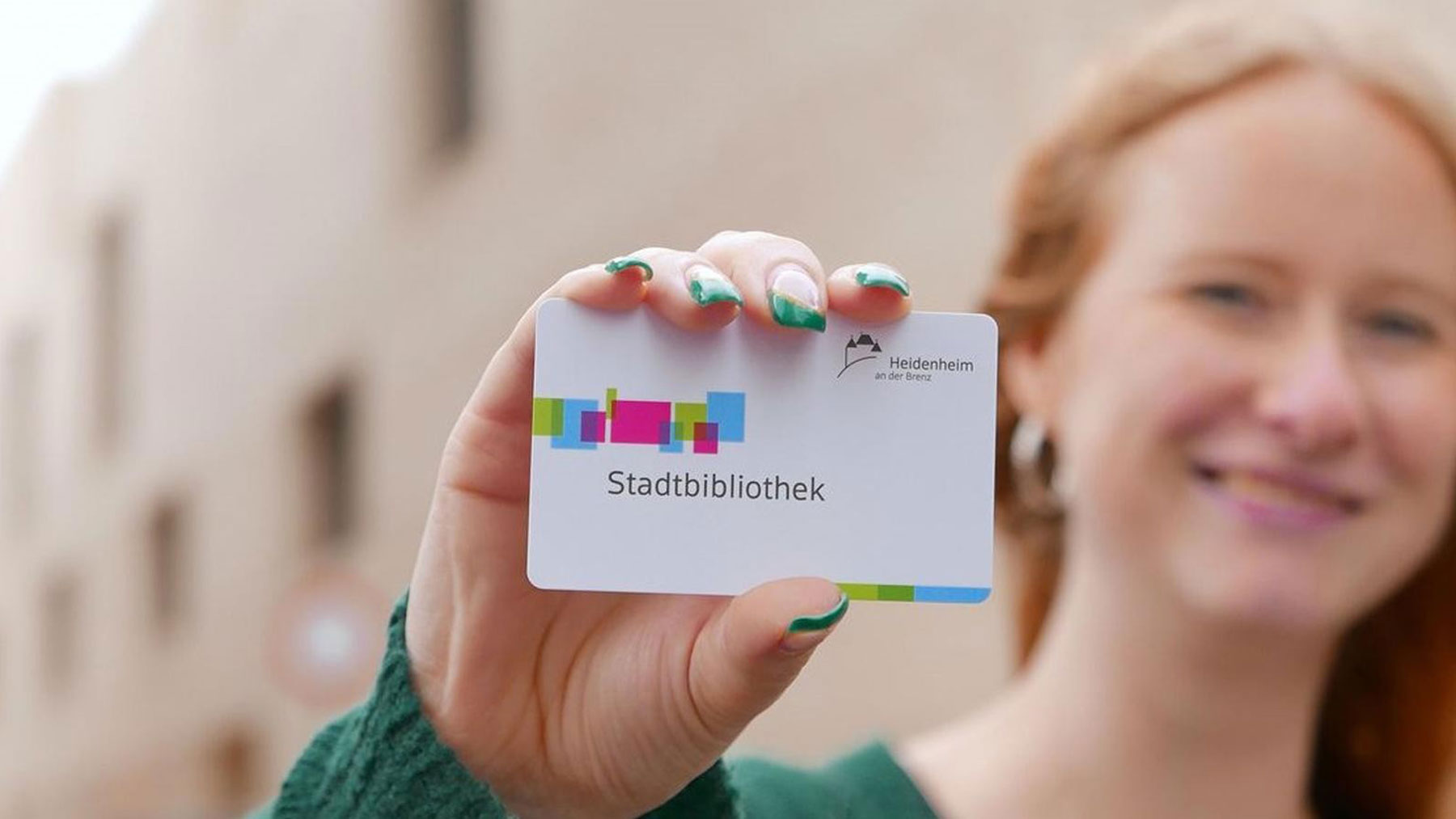 Woman holding a membership card of the library of the city Heidenheim