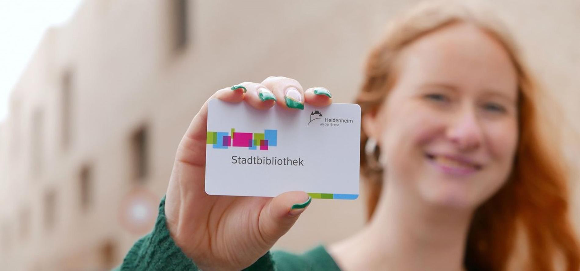 Girl showing a smart card with the inscription Stadbibliothek Heidenheim